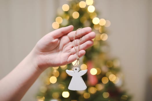 Decorating Christmas tree, holding Christmas toy in a hand. Holiday, Christmas and New Year family celebration concept.