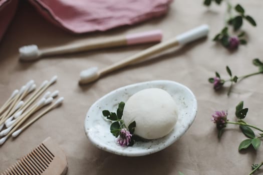 Soap bar or solid shampoo on a soap dish, bamboo toothbrush and towel top view with copyspace. Accessories for personal hygiene. Plastic free and eco friendly products in household.