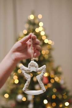 Decorating Christmas tree, holding Christmas toy in a hand. Holiday, Christmas and New Year family celebration concept.