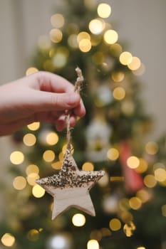 Decorating Christmas tree, holding Christmas toy in a hand. Holiday, Christmas and New Year family celebration concept.