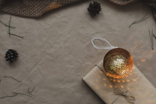 Christmas composition. Gift, fir tree branches, balls on craft paper background. Christmas, winter, new year concept. Flat lay, top view, copy space.