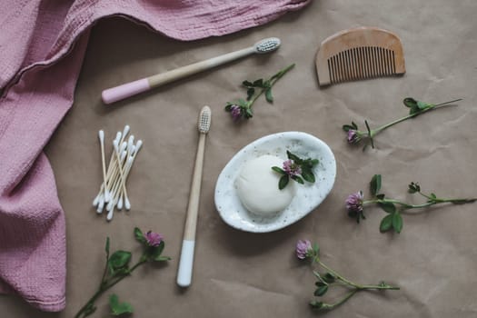 Soap bar or solid shampoo on a soap dish, bamboo toothbrush and towel top view with copyspace. Accessories for personal hygiene. Plastic free and eco friendly products in household.