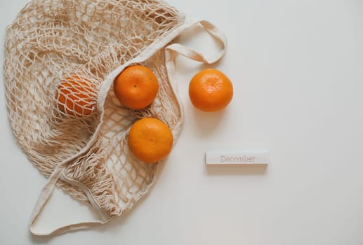Christmas or New Year composition with fresh tangerines in shopping bag and word December.