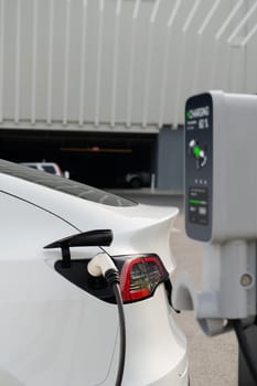 EV electric car recharge battery at parking lot in city commercial zone or mall. Alternative clean energy technology for rechargeable automobile for sustainable and eco friendly travel. Expedient