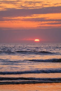 Ocean waves on sunset with setting sun background