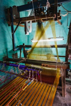 Man weaving silk sari on loom. in Kanchipuram, Tamil Nadu, India. Kanchipuram is famous for hand woven silk sarees and most of the city's workforce is involved in weaving industry