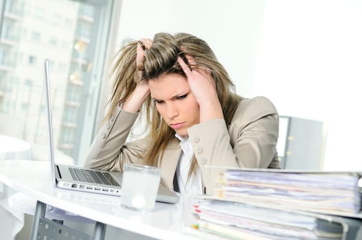 young woman stressed at work, taking an aspirin cahet