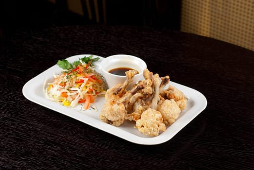 Fried chicken wings garnished with fresh vegetables with Teriyaki sauce