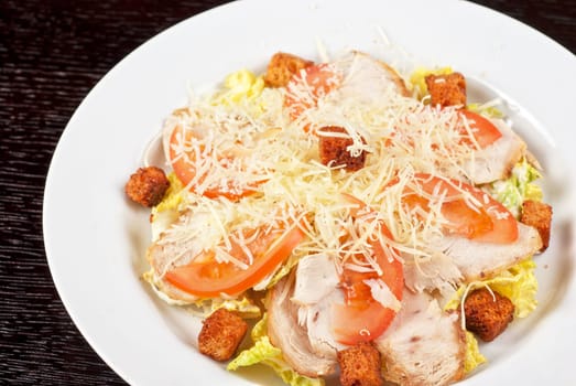 Salad of lettuce, chinese cabbage, tomato, garlic rusk, parmesan cheese, sauce and chicken meat