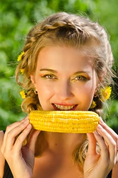 Close-up outdoor portrait of young beauty woman eating corn-cob