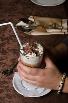 Closeup of female hands holding cup of latte