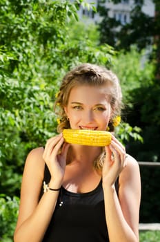 Close-up outdoor portrait of young beauty woman eating corn-cob