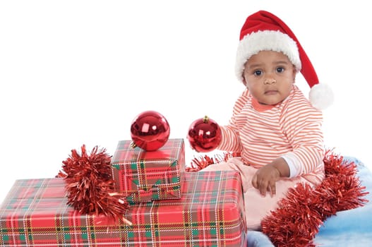 Adorable baby girl with christmas presents and santa hat