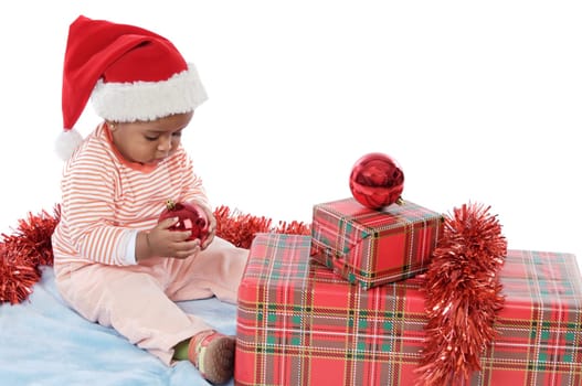 Adorable baby girl with christmas presents and santa hat