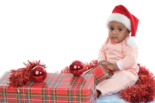 Adorable baby girl with christmas presents and santa hat