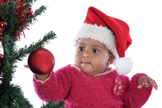 Adorable baby girl playing with christmas tree over white background