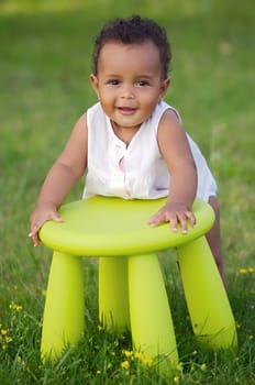Adorable toddler playing with a chair in the garden