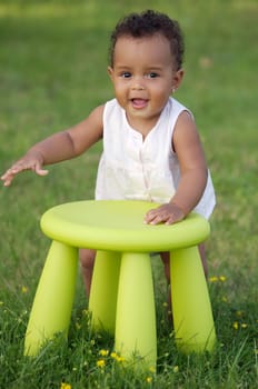 Adorable toddler playing with a chair in the garden