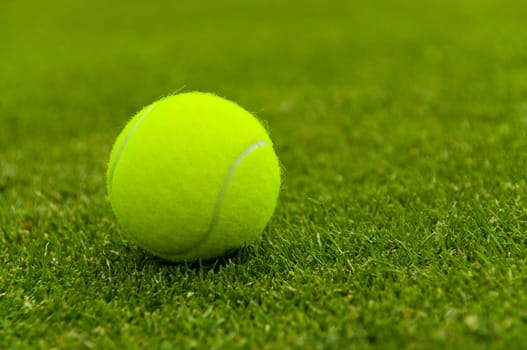 Yellow tennis ball on lawn court