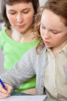 Teenager girl sitting together with her mother and showing her homework