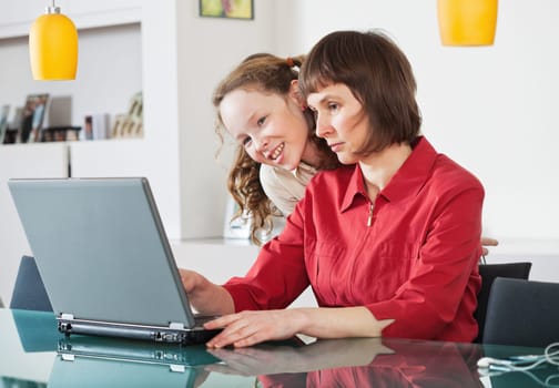 Mother and teenager girl with laptop computer together at home
