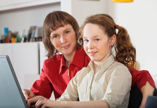 Portrait of mother and teenager girl with laptop computer  at home