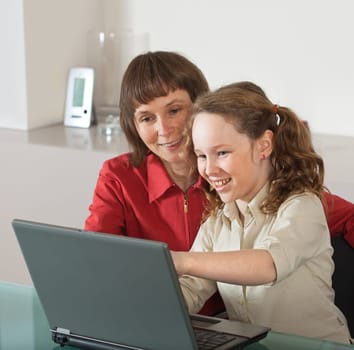 Mother and teenager girl with laptop computer together at home
