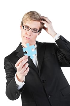 Young blond handsome businessman in glasses holds puzzle piece