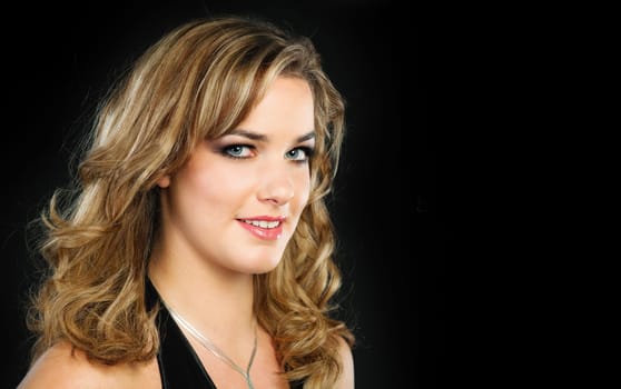 Portrait of a pretty young woman with long blond hair photoraphed on dark barkground
