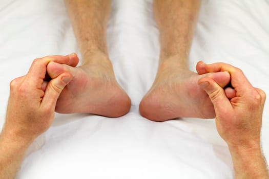 Big toes of both feet of an adult male receiving massage from a reflexologist as part of a treatment to promote circulation.