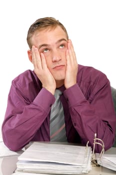 Exhausted man in office with files in front of him. He holds his hands to his face and looks up sadly