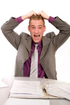 Desperate businessman in office at desk. He holds his hands above his head and screams. In front of him is a file folder.