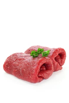 Two raw beef roulades against white background
