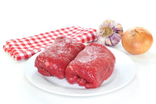 Two raw beef roulades against white background