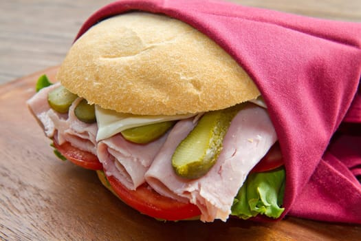 sandwiches with ham and vegetables on wooden board