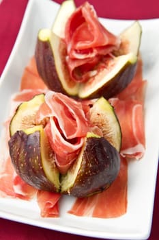 Fresh figs with ham on a white plate