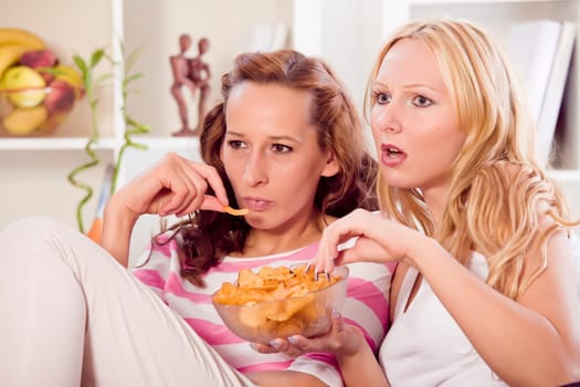 two women friends watching television in living room