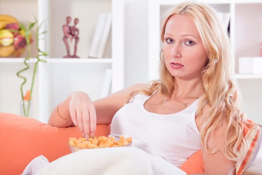 relaxed woman sitting on sofa with unhealthy snack