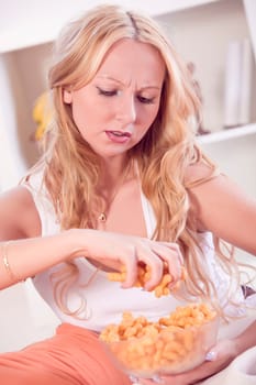 frustrated woman eating chips on sofa