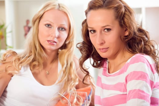 two women friends sitting relaxed on sofa at home