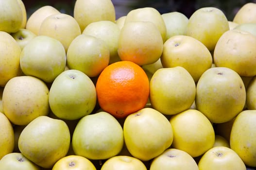 accumulated apples whit a orange in a store of fruits