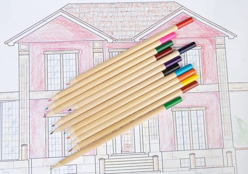 pencils of colors on drawing of one house