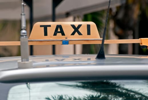 Taxi sign on the roof of an old car.