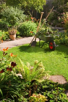 Work in summer garden in the morning with wheelbarrow, shovel and rake - vertical