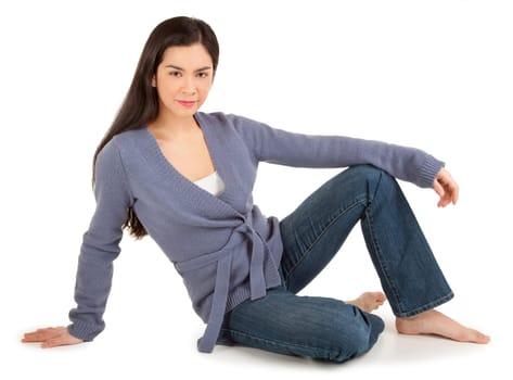 Beautiful casually dressed lady sitting on the floor and looking at the camera isolated on white.