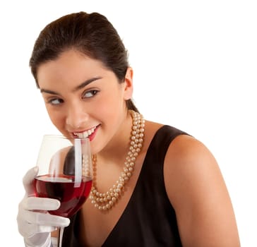 A beautiful smiling woman in a classy dress is holding a glass of red wine and looking sideways.