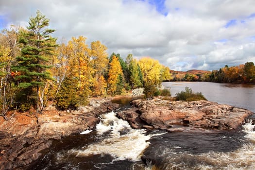 This is a beautiful view of a cascading river on a fall day.