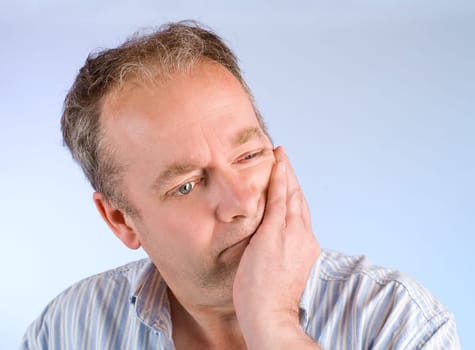 A man is thinking about something while leaning on his hand.
