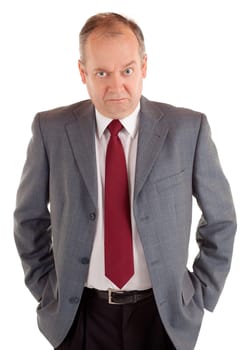 A businessman is standing and seriously looking at the camera with a scowling expression.