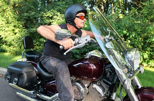 A middle-aged man is riding a motorcycle.